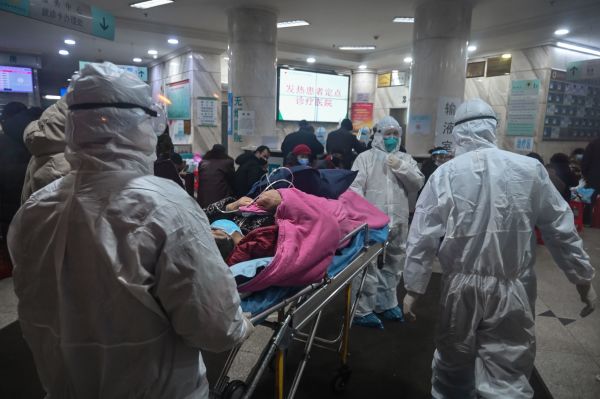 在这张拍摄于2020年1月25日的照片中，身穿防护服的医护人员带着一名此前未知的冠状病毒患者来到武汉市红十字会医院