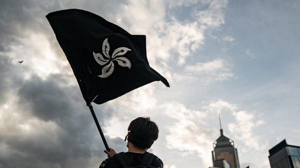 2019年7月1日，一名反送中示威者在立法會大樓外，揮舞黑色的抗爭旗幟。
