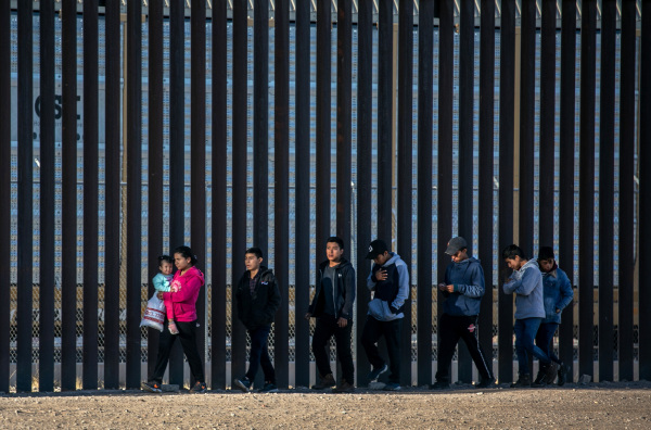2021年3月17日，在墨西哥华雷斯市，无证移民穿过浅里奥格兰德河进入埃尔帕索，沿着美国和墨西哥边境墙行走。