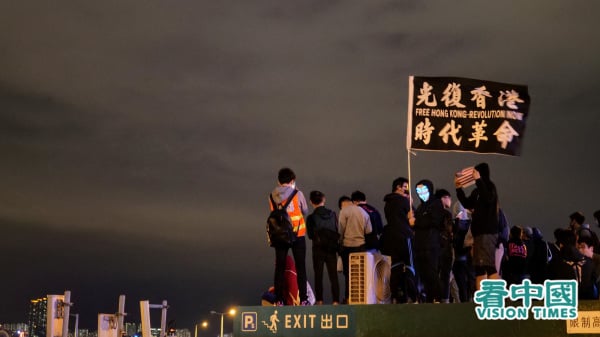 中共在香港大動干戈，它到底懼怕什麼？圖為反送中集會上，有抗爭人士高舉「光復香港 時代革命」旗幟。（圖片來源：龐大衛/看中國）