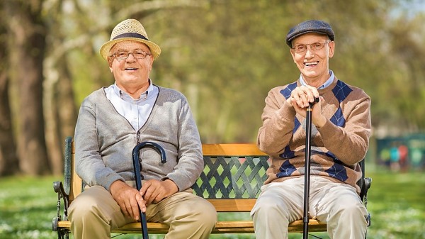 2個老人坐在公園的椅子上晒太陽