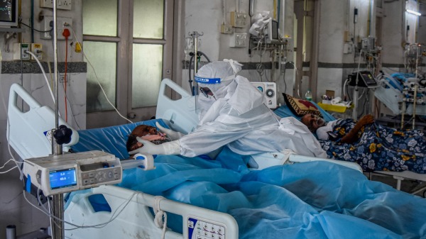医护人员在ICU病房照顾一名COVID-19患者。
