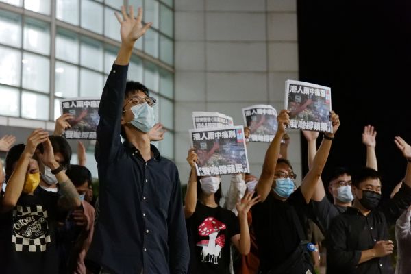 图为2021年6月24日，香港《苹果日报》的记者们手举最后一期报纸向支持者们致意。 