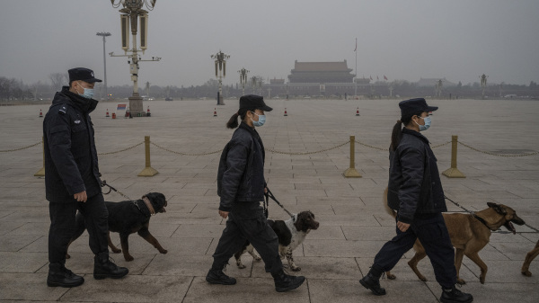 牽著警犬的警察在空曠的天安門廣場上巡邏。