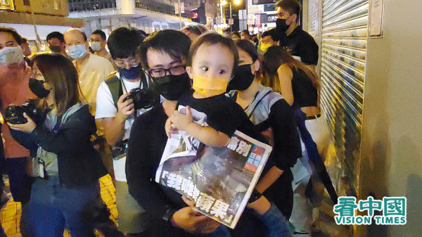 港人手抱幼儿排队购买最后一期《苹果》。（图片来源：李天正/看中国）