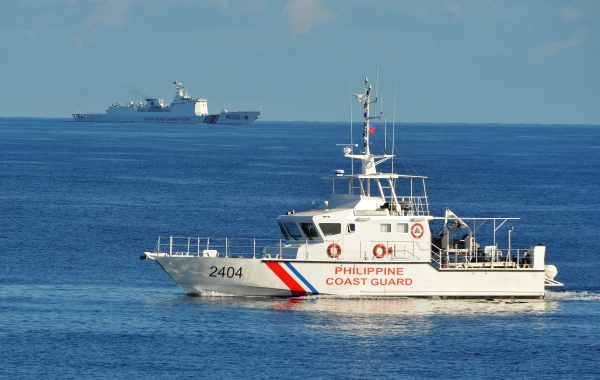 图为2019年5月14日，一艘菲律宾海警船和美国在南中国海进行联合搜救演习时，远处有一艘中共海警船在进行监视活动。
