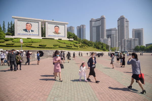 朝鲜平壤清津街的一个广场,行人从金日成和金正日的肖像前穿过