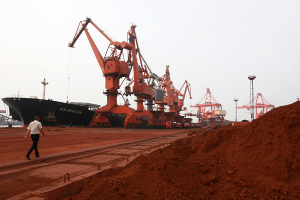 图为2010年9月5日，中国江苏省连云港的一个港口，大型推土机在把含有稀土的土壤装载到货船上用于出口。 