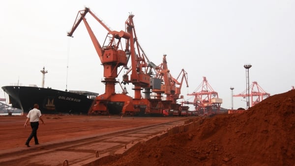 图为2010年9月5日，中国江苏省连云港的一个港口，大型推土机在把含有稀土的土壤装载到货船上用于出口。