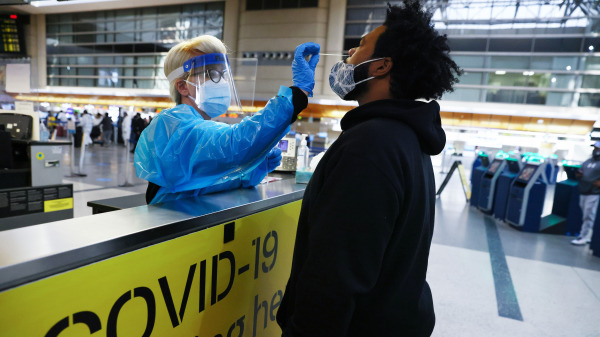 在美国洛杉矶国际机场，旅客接受鼻拭子COVID-19测试