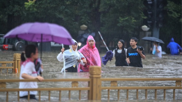 2021年7月20日中國救生中部河南省鄭州市暴雨後人們涉水走過街道。2(16:9)