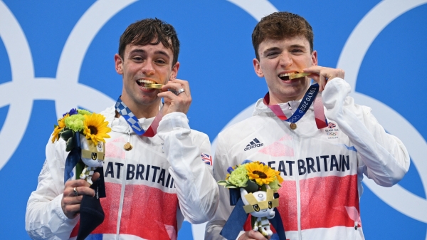英国跳水名将汤姆・戴利(左) 与搭档马蒂・李(右)对着镜头做出咬金牌的姿势