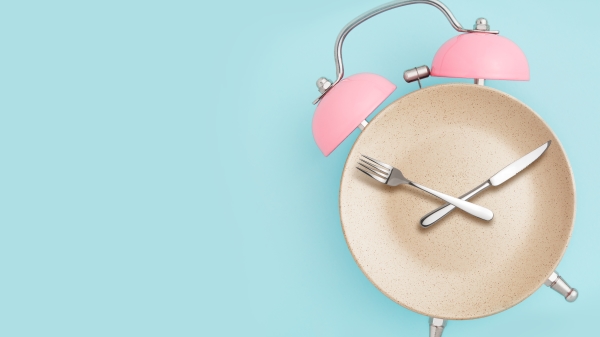 鬧鐘和帶餐具的盤子。間歇性禁食、午餐時間、飲食和減肥的概念