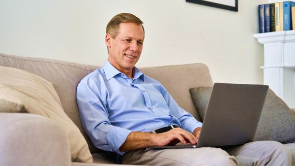 一個男人坐在沙發上打電腦