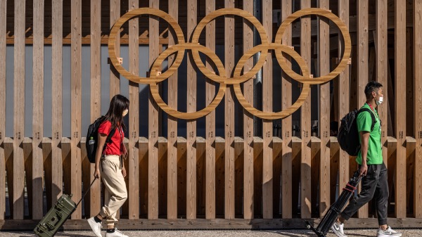 外國記者攜帶廣播設備步行前往日本東京奧運會運動員村媒體中心。