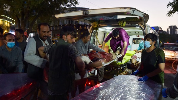 2021年8月26日，医务人员和义工正将一名在阿富汗喀布尔机场附近恐怖袭击爆炸中的伤者送医。（图片来源：WAKIL KOHSAR/AFP via Getty Images)