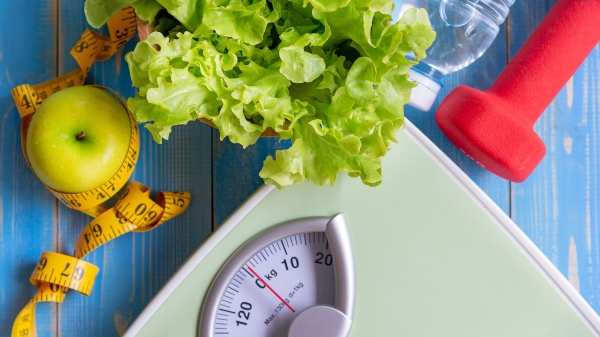 飲食和健康生活理念。青蘋果和體重秤用新鮮蔬菜、清潔水和運動器材測量水龍頭，用於女性減肥瘦身