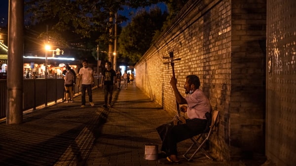2021年8月24日的北京，一名男子在購物區的街道上演奏音樂，艱難求生。