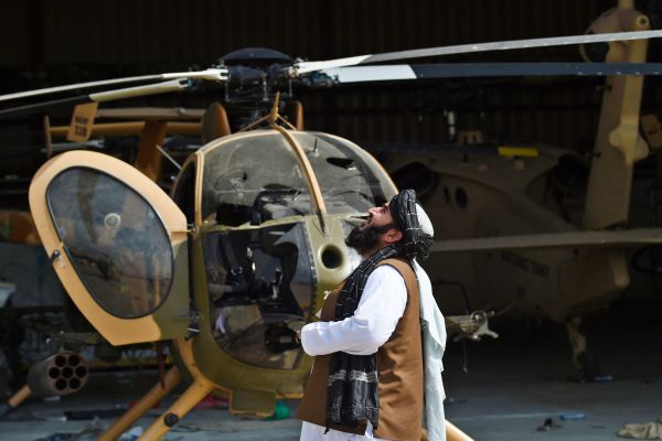 2021年8月31日，一名塔利班成員站在喀布爾機場一架損壞的直升機旁抬頭仰望。